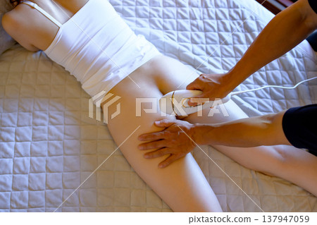 女性在伴侶（男友、丈夫）的幫助下，俯臥使用家用除毛儀進行 VIO 除毛。 137947059