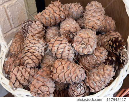 Pine cones fill wicker basket creating natural texture with earthy brown tones and layered organic pattern. Nature texture background, rustic decor element, seasonal design, craft material Pine cones fill wicker basket creating natural texture with earthy brown tones and layered organic pattern. Nature texture background, rustic decor element, seasonal design, craft material 137948417