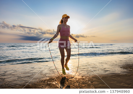 Fit woman jumping rope at the beach during summer vacation 137948960