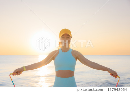 Fit woman jumping rope at the beach during summer vacation Fit woman jumping rope at the beach during summer vacation 137948964