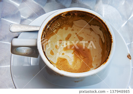 Empty espresso cup with crema stains on saucer at cafe table. Top view. Selective focus Empty espresso cup with crema stains on saucer at cafe table. Top view. Selective focus 137948985