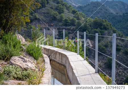 Scenic view of surrounding mountains and picturesque village from a hiking trail along an old irrigation ditch in Frigiliana, Spain. 137949273
