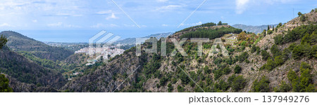 Scenic view of surrounding mountains and picturesque village from a hiking trail along an old irrigation ditch in Frigiliana, Spain. Scenic view of surrounding mountains and picturesque village from a hiking trail along an old irrigation ditch in Frigiliana, Spain. 137949276