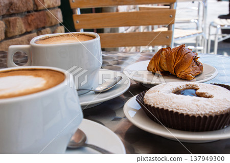Cozy breakfast with two cappuccinos, heart decorated chocolate cupcake and sfogliatella pastry. Romantic date or a friendly morning meetup on a hot summer day. Cozy breakfast with two cappuccinos, heart decorated chocolate cupcake and sfogliatella pastry. Romantic date or a friendly morning meetup on a hot summer day. 137949300
