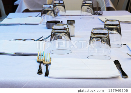 Minimalist dining table setting with white tablecloth, cutlery, glassware, ready for guests Minimalist dining table setting with white tablecloth, cutlery, glassware, ready for guests 137949306
