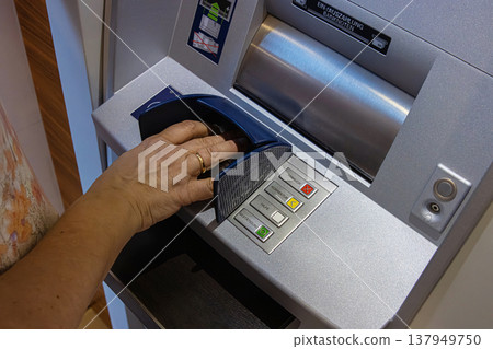 Person using the keypad of an ATM interface labeled in German to enter information or PIN for a secure transaction. Closeup of a hand over keypad pressing buttons Person using the keypad of an ATM interface labeled in German to enter information or PIN for a secure transaction. Closeup of a hand over keypad pressing buttons 137949750