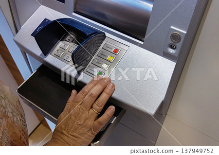 Senior Hand Using ATM. Keypad. A closeup of a person hand pressing the green button on an ATM keypad while withdrawing or managing money. Senior Hand Using ATM. Keypad. A closeup of a person hand pressing the green button on an ATM keypad while withdrawing or managing money. 137949752