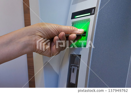 Closeup of a person hand inserting a bank card into an ATM machine slot for money withdrawal Closeup of a person hand inserting a bank card into an ATM machine slot for money withdrawal 137949762