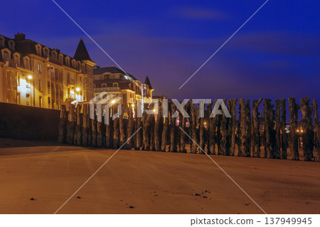 Wooden breakwaters and illuminated beachfront at night in Saint Malo France 137949945