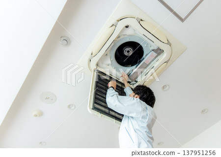 A male worker who maintains an air conditioner A male worker who maintains an air conditioner 137951256