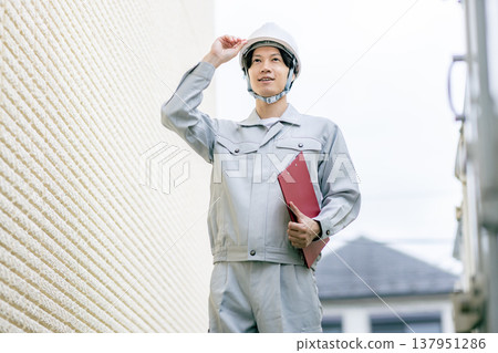 A man in work clothes inspects the exterior walls. A man in work clothes inspects the exterior walls. 137951286
