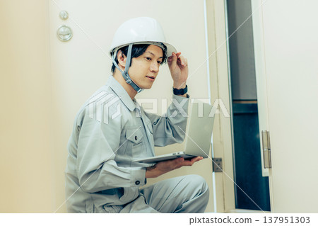 Wearing a helmet, working on a construction site, with blueprints and site supervisor. Wearing a helmet, working on a construction site, with blueprints and site supervisor. 137951303