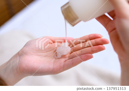 A young woman dispenses hand cream into her palm. Hand gel. Trimming up. 137951313