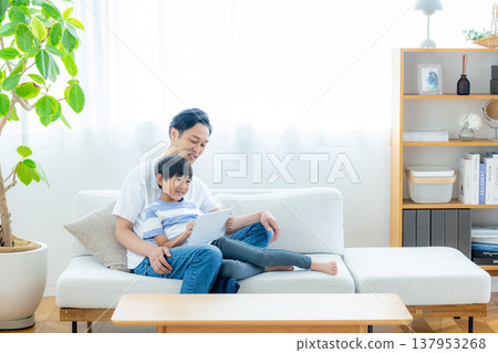 A family sitting on the sofa watching a tablet A family sitting on the sofa watching a tablet 137953268
