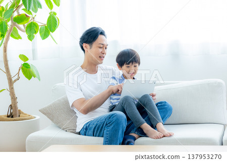 A family sitting on the sofa watching a tablet 137953270