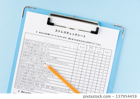 A stress check sheet in a binder with a pencil against a light blue background. 137954459
