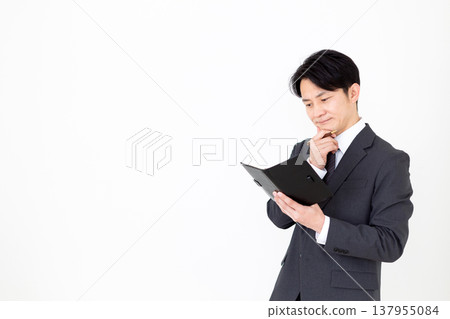 A middle-aged businessman carrying a black notebook, troubled by his worries. A middle-aged businessman carrying a black notebook, troubled by his worries. 137955084