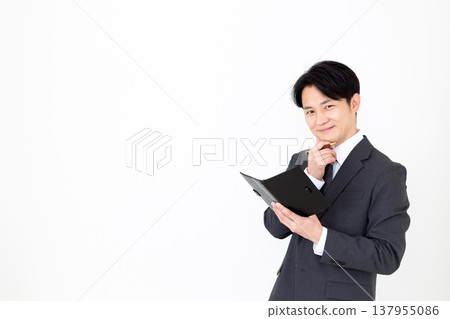 A middle-aged businessman carrying a black notebook. A middle-aged businessman carrying a black notebook. 137955086