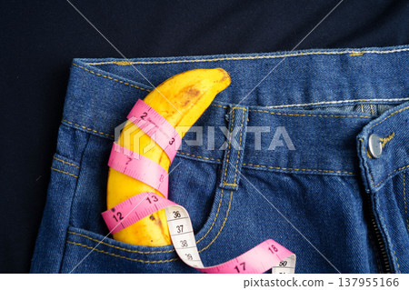 Banana with measuring tape on jean trousers, penis health. 137955166