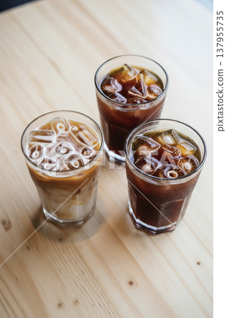 Three types of iced coffee in glasses placed on a wood-grain table. 137955735