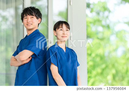 身穿手術服的男女醫護人員(物理治療師、護士、技術人員)站在醫院和醫療機構前。 身穿手術服的男女醫護人員(物理治療師、護士、技術人員)站在醫院和醫療機構前。 137956084