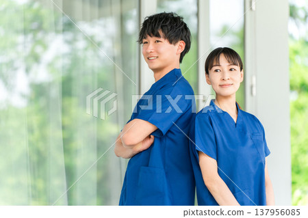 身穿手術服的男女醫護人員（物理治療師、護士、技術人員）站在醫院和醫療機構前。 137956085