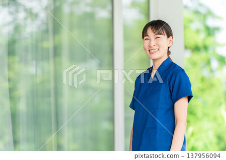 Female healthcare staff wearing scrubs standing in front of the hospital/facility. Female healthcare staff wearing scrubs standing in front of the hospital/facility. 137956094