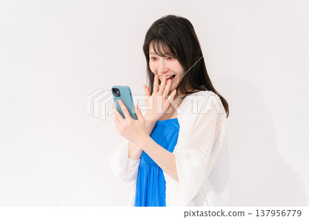A woman with a smartphone is surprised. A woman with a smartphone is surprised. 137956779