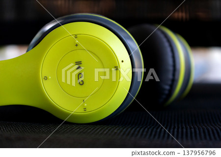 close up of lime green and black wireless headphones on dark background 137956796