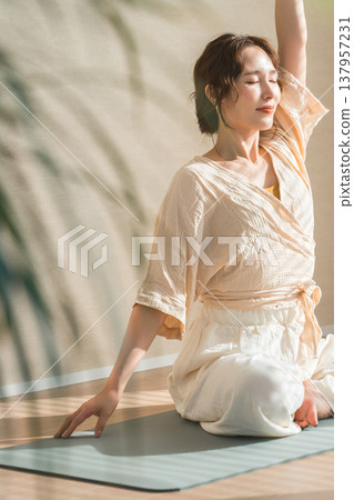 一位女士在家裡的客廳裡做瑜伽（放鬆，保健） 137957231