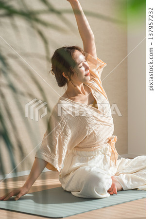 一位女士在家裡的客廳裡做瑜伽(放鬆,保健) 一位女士在家裡的客廳裡做瑜伽(放鬆,保健) 137957232
