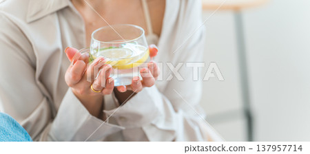 一位女士正在喝排毒水、檸檬水和薄荷水,她的手就放在她手上。 一位女士正在喝排毒水、檸檬水和薄荷水,她的手就放在她手上。 137957714
