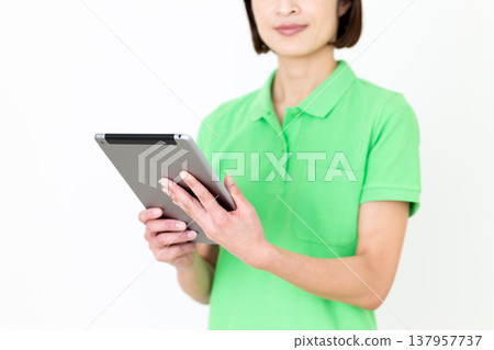 A middle-aged female care worker holding a tablet. A middle-aged female care worker holding a tablet. 137957737
