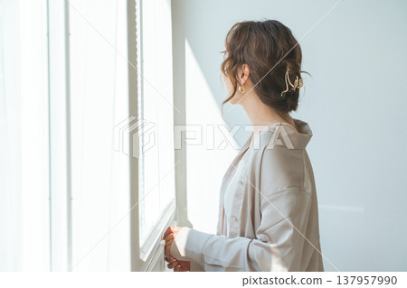 一位衣著時尚的女士站在客廳窗邊。 137957990