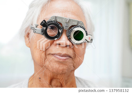 Asian senior woman wearing ophthalmic vision eye test and using optical trial frame. Asian senior woman wearing ophthalmic vision eye test and using optical trial frame. 137958132