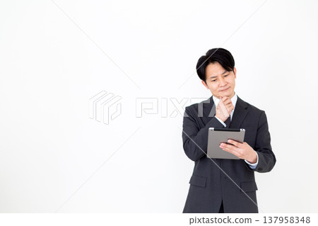 一位中年商人正在費力地使用平板電腦。 137958348