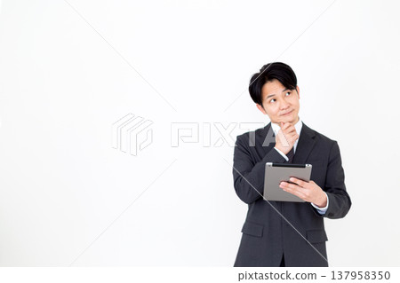 A middle-aged businessman struggling with a tablet. A middle-aged businessman struggling with a tablet. 137958350