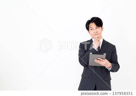 一位中年商人正在費力地使用平板電腦。 一位中年商人正在費力地使用平板電腦。 137958351