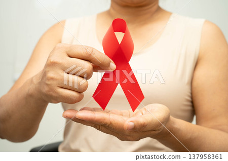 Asian woman with red ribbon for December world AIDS day. AIDS and HIV awareness. 137958361