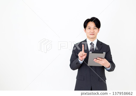 A middle-aged businessman holding a tablet and raising his index finger. 137958662