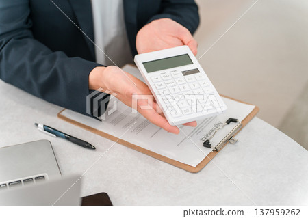 A male businessman's hands as he displays numbers on a calculator. A male businessman's hands as he displays numbers on a calculator. 137959262