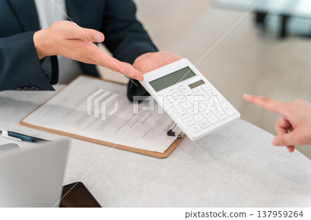 一位男商人正在用計算器顯示數字，他的雙手在螢幕上揮舞。 137959264