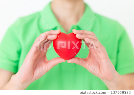 A middle-aged female care worker holding a heart-shaped model. A middle-aged female care worker holding a heart-shaped model. 137959583