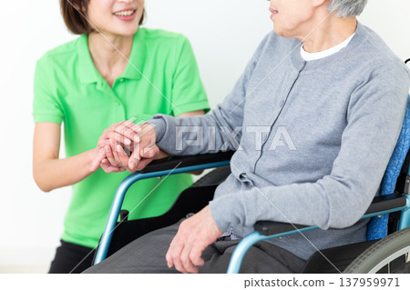 A care worker assisting an elderly person in a wheelchair. 137959971