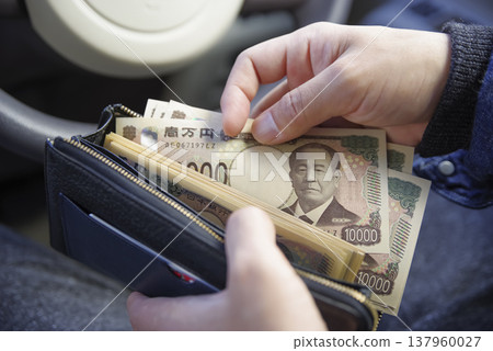 一名男子將現金放入錢包。 137960027
