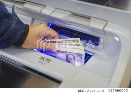 A man's hands as he withdraws money from an ATM 137960035