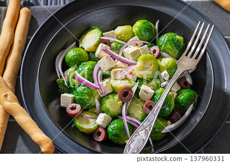 Mediterranean brussels sprouts salad with feta cheese, olives and red onion in black bowl Mediterranean brussels sprouts salad with feta cheese, olives and red onion in black bowl 137960331