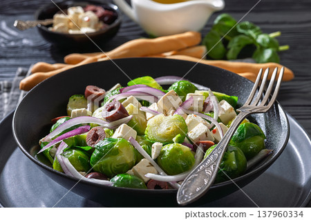 Mediterranean brussels sprouts salad with feta cheese, olives and red onion in black bowl  137960334