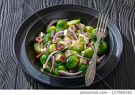 Mediterranean brussels sprouts salad with feta cheese, olives and red onion in black bowl Mediterranean brussels sprouts salad with feta cheese, olives and red onion in black bowl 137960340