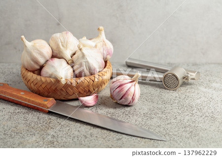 Garlic and garlic press on a kitchen table. Garlic and garlic press on a kitchen table. 137962229